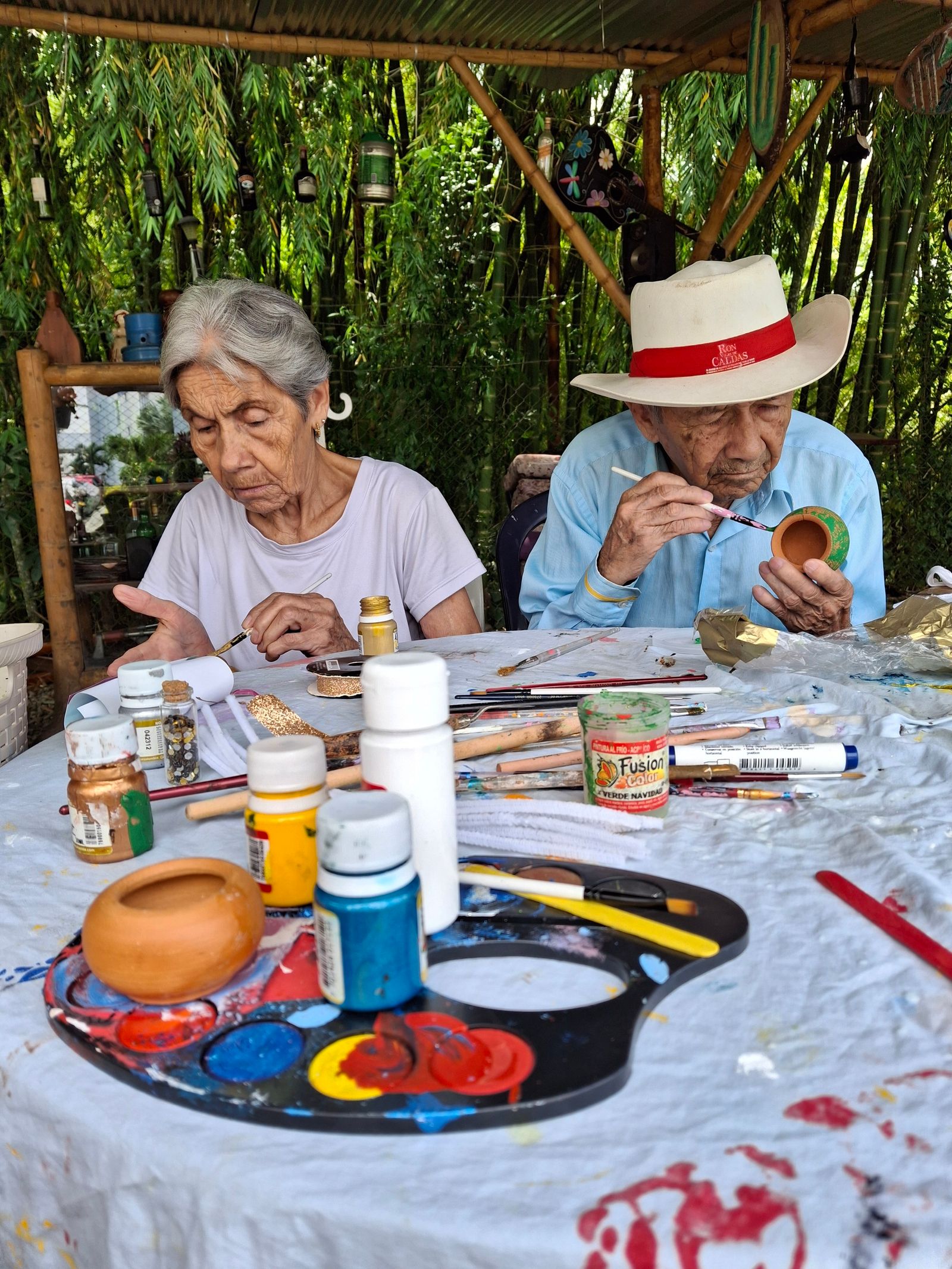 Senior artists engaged in pottery painting together outdoors
