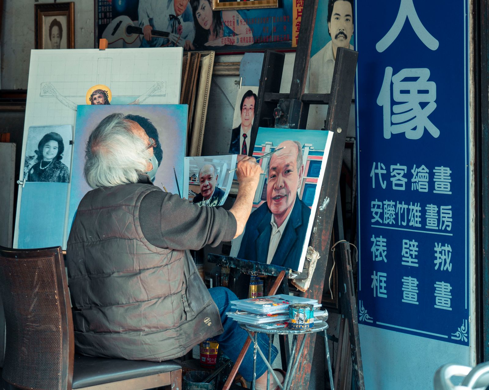 An elderly man doing portrait painting in a creative studio
