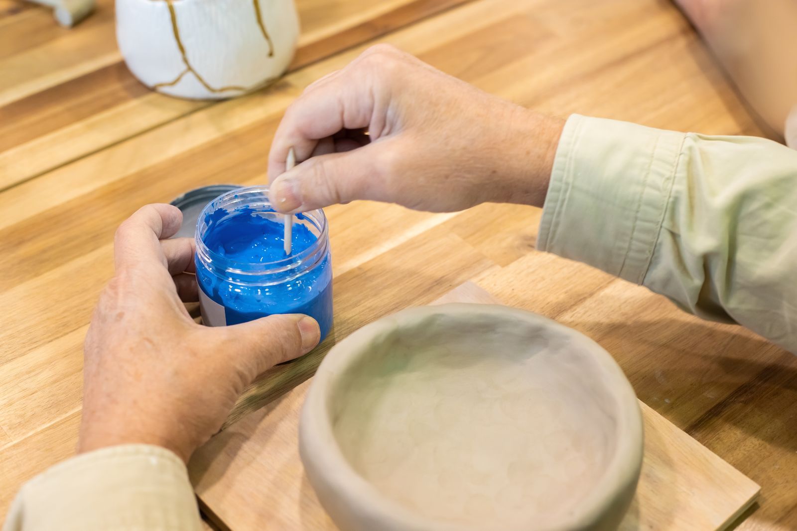 An artisan mixing bright blue paint in a studio